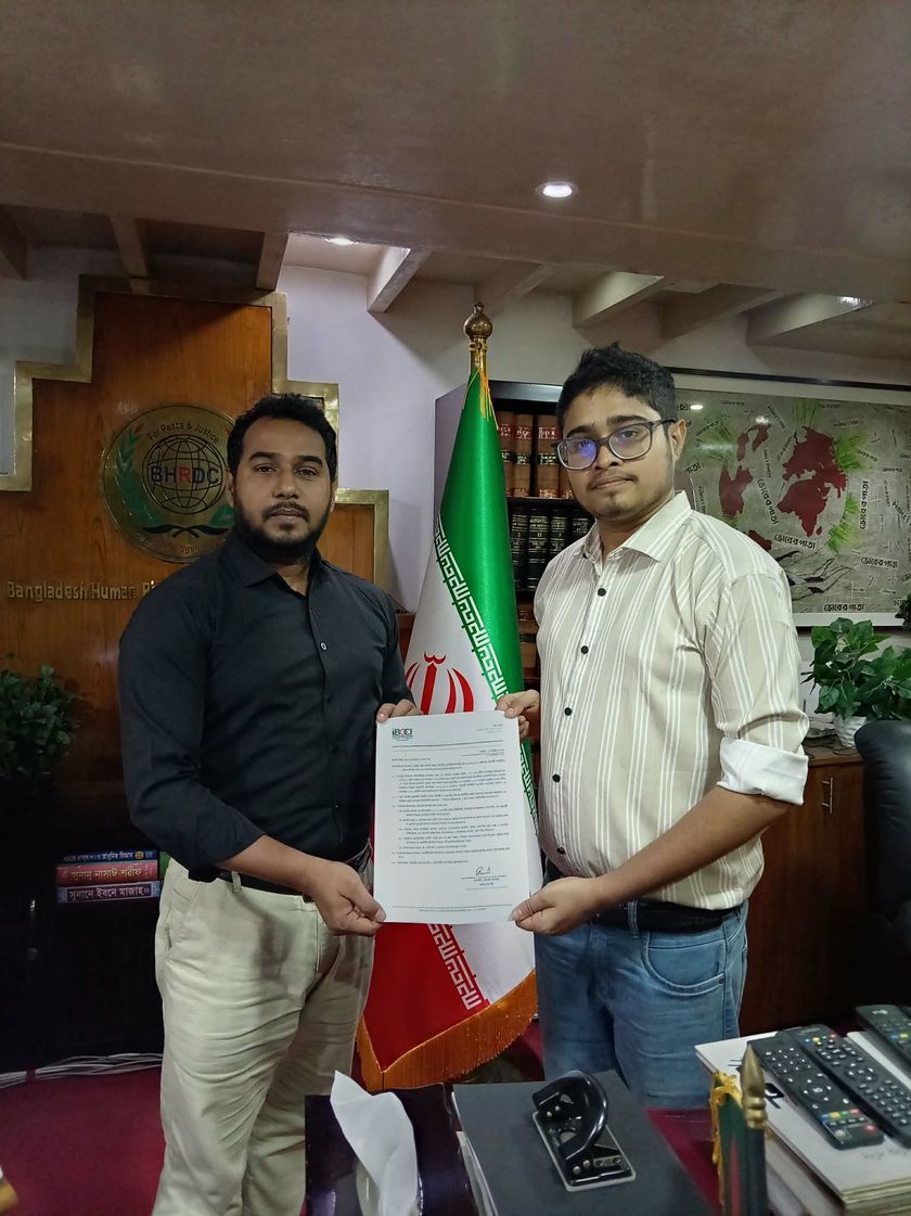 Two men holding the IBCCI letter of appointment in front of the flag of Iran